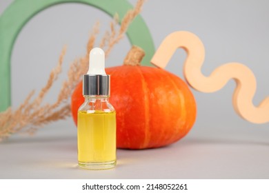 Mockup Image Of Dropper Bottle With Natural Organic Cosmetic Oil - Pumpkin Seed Oil Extract For Skincare Or Hair With Pumpkins As Background. Beauty Treatment, Herbal Cosmetics.  Selective Focus