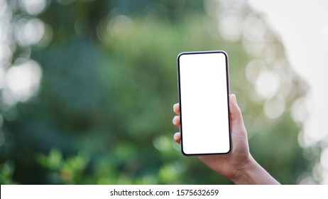 Mockup Image Of A Hand Holding Black Mobile Phone With Blank Desktop Screen With Green Nature Background