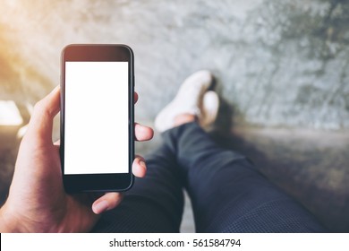 Mockup image of hand holding black mobile phone with blank white screen  with white canvas shoes on concrete polishing wall - Powered by Shutterstock