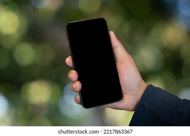 Mockup Image Of Hand Holding Mobile Phone With Blank White Green Nature Background.