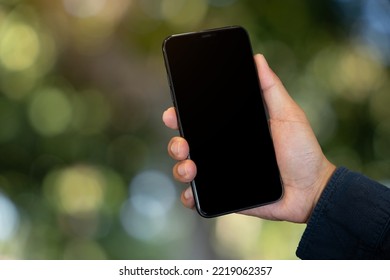 Mockup Image Of Hand Holding Mobile Phone With Blank White Green Nature Background.