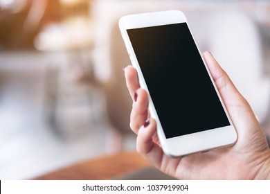 Mockup Image Of A Hand Holding White Mobile Phone With Blank Black Desktop Screen With Blur Background