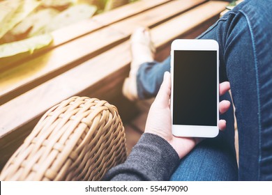 Mockup Image Of Hand Holding White Mobile Phone With Blank Black Screen On Thigh 