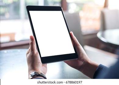 Mockup Image Of Hands Holding Black Tablet Pc With White Blank Screen In Modern Cafe