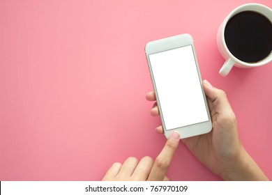 Mockup Image Of Hands Holding White Mobile Phone With Blank White 
Screen With  Modern Pink Office Desk With Laptop And Other Supplies For Input The Text On Copy Space Top View, Flat Lay.