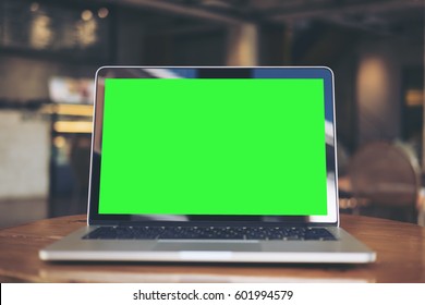 Mockup Image Of Laptop With Blank Green Screen On Wooden Table In Vintage Cafe