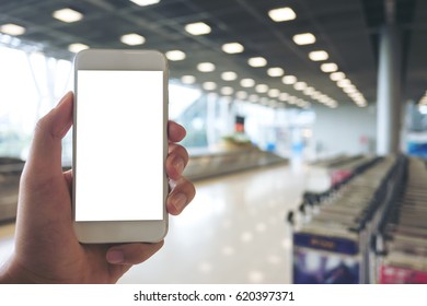 Mockup Image Of A Man Holding White Mobile Phone With Blank White Screen While Standing And Waiting For Baggage Claim In The Airport