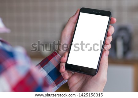 Mockup image: man looking at black smartphone with white blank screen. Close up view of man hands with smart phone mobile device. Mock up, copyspace, template and technology concept 