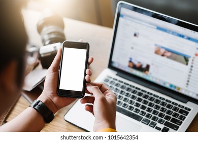 Mockup Image Of A Man's Hand Holding White Mobile Phone With Blank Black Desktop Screen On Thigh In Cafe