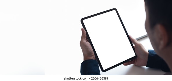 Mockup Image Of Man's Hand Holding Blank White Screen Digital Tablet On White Black Ground, Over Shoulder View