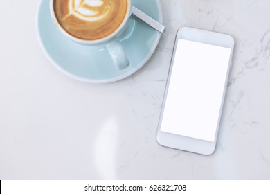 Mockup Image Of Mobile Phone With Blank White Screen And Blue Coffee Cup With Latte Art On Marble Table In Cafe