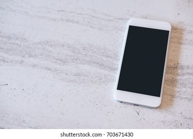 Mockup Image Of White Mobile Phone With Blank Black Screen On Marble Table In Cafe