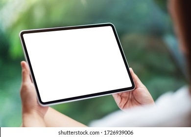 Mockup image of a woman holding black tablet pc with blank white desktop screen , green nature background - Powered by Shutterstock