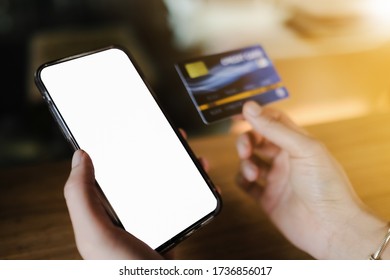 Mockup Image Of Hand’s Woman Holding Black Mobile Phone And Credit Card With Blank Screen In Cafe.