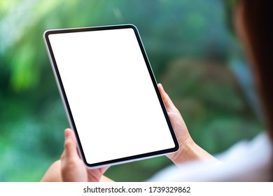 Mockup image of a woman holding black tablet pc with blank white desktop screen , green nature background - Powered by Shutterstock