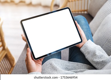 Mockup image of a woman holding black tablet pc with blank desktop white screen while lying on a sofa at home - Powered by Shutterstock