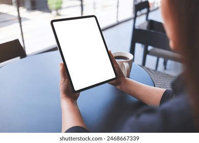 Mockup image of a woman holding digital tablet with blank white desktop screen in cafe - Powered by Shutterstock