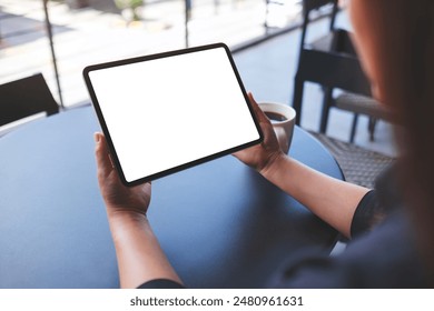 Mockup image of a woman holding digital tablet with blank white desktop screen in cafe - Powered by Shutterstock