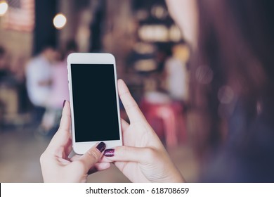 Mockup Image Of A Woman Holding Mobile Phone With Blank Black Screen In Modern Loft Cafe