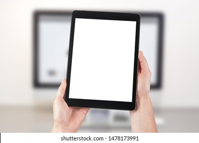 Mockup image of a woman holding a tablet and in the background a desktop computer with a laptop. Blank screen with copy space. - Powered by Shutterstock