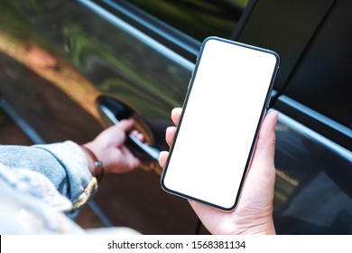 Mockup Image Of A Woman Holding And Using Mobile Phone With Blank Screen While Opening The Car Door