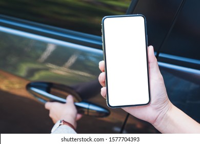 Mockup Image Of A Woman Holding And Using Mobile Phone With Blank Screen While Opening The Car Door