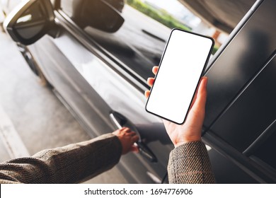 Mockup Image Of A Woman Holding And Using Mobile Phone With Blank Screen While Opening The Car Door