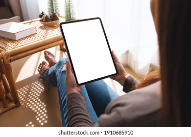 Mockup image of a woman holding and using tablet pc with blank desktop white screen at home - Shutterstock ID 1910685910