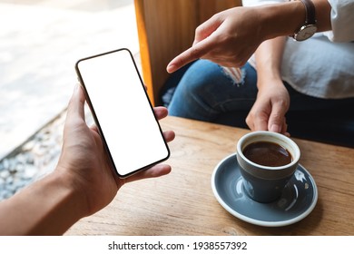 Mockup Image Of A Woman Pointing At A White Mobile Phone With Blank Black Desktop Screen In A Man's Hand