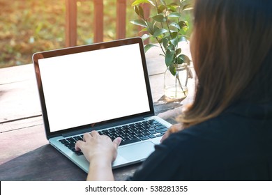 Mockup image of a woman using laptop with blank white screen on vintage wooden table in nature outdoor park - Powered by Shutterstock