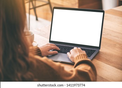 Mockup Image Of A Woman Using And Typing On Laptop Computer Keyboard With Blank White Desktop Screen With Coffee Cup On Wooden Table 