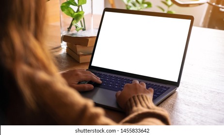 Mockup Image Of A Woman Using And Typing On Laptop With Blank White Desktop Screen On Wooden Table