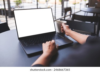 Mockup image of a woman working on laptop computer with blank white desktop screen while drinking coffee in cafe - Powered by Shutterstock