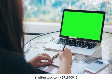 Mockup Image Of A Woman Writing And Using Laptop With Blank Green Screen By Swimming Pool