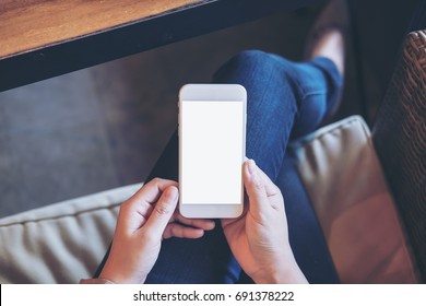 Mockup Image Of Woman's Hands Holding White Mobile Phone With Blank Screen On Thigh In Office