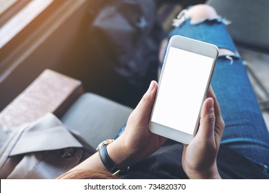 Mockup Image Of Woman's Hands Holding White Mobile Phone With Blank Black Screen On Thigh 