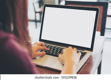 Mockup image of women using laptop with blank white screen on vintage wooden table in loft cafe