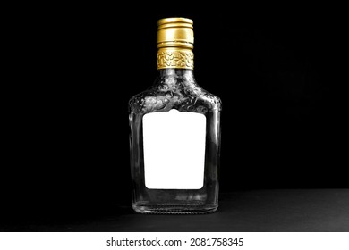 Mockup Label On Empty Glass Bottle Of Whiskey, Cognac Or Vodka On A Black Background. Template, Copy Space