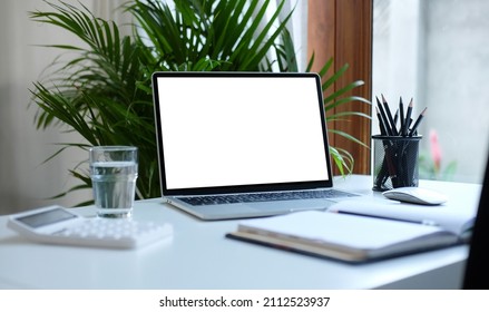 Mockup laptop computer, book, calculator, glass and pencil holder on white table. - Powered by Shutterstock