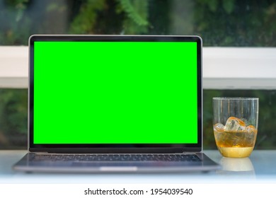 Mockup of laptop computer with empty screen with Iced coffee in a glass cup isolate on wooden office desk in coffee shop like the background,White screen