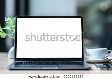 Mockup of laptop computer with empty screen with coffee cup and smartphone on table of the coffee shop background,White screen