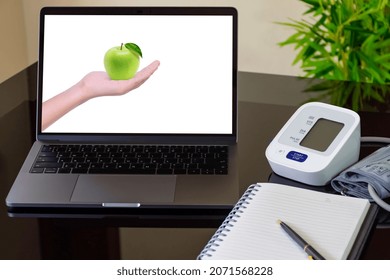 Mockup Laptop Computer With Female Hand Hold Green Apple On Screen With Digital Blood Pressure Guage (sphygmomanometer) And Diary Notebook On The Office Desk