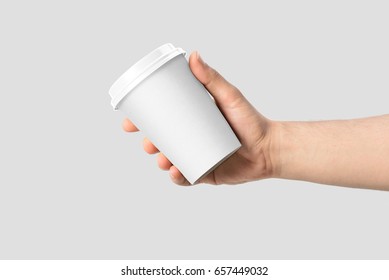 Mockup of male hand holding a Coffee paper cup isolated on light grey background. 
