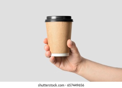 Mockup Of Male Hand Holding A Coffee Paper Cup Isolated On Light Grey Background. 