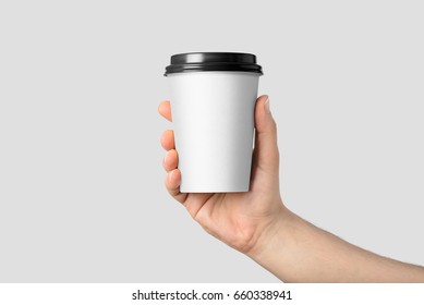 Mockup of male hand holding a Coffee paper cup isolated on light grey background.  - Shutterstock ID 660338941