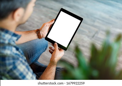 Mockup of a man holds tablet computer with isolated screen in his hands. View from above. Clipping path.