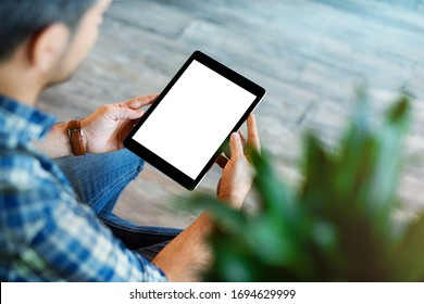 Mockup of a man holds tablet computer with isolated screen in his hands. View from above. Clipping path.