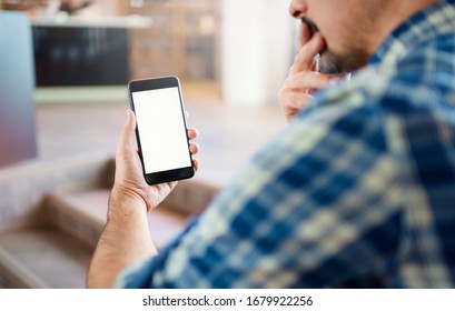 Mockup of a man in thoughts that holding a smartphone in his hand. Close up shot. Clipping path included.