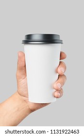 Mockup of men's hand holding white paper large size cup with black cover isolated on grey background