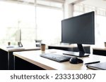 Mockup of modern personal desk office with monitor display, keyboard, mouse, notebook, pen and a paper coffee cup on the table in modern workspace. Image with copy space.